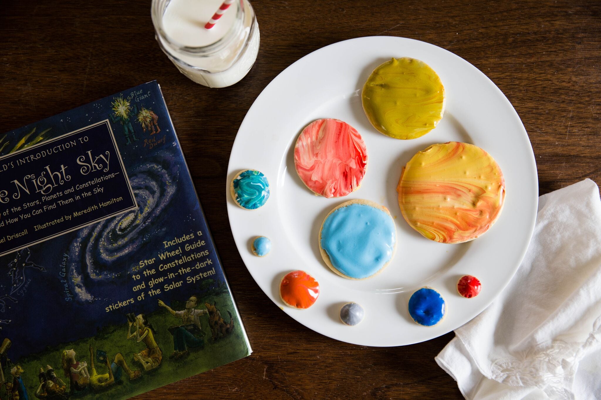 Homeschool Sample Craft, planet cookies on a plate next to a jar of milk and a book about the night sky.