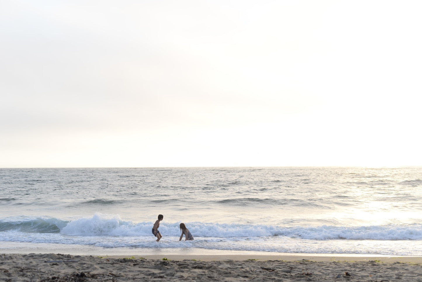 Two kindergarten kids play in the ocean.