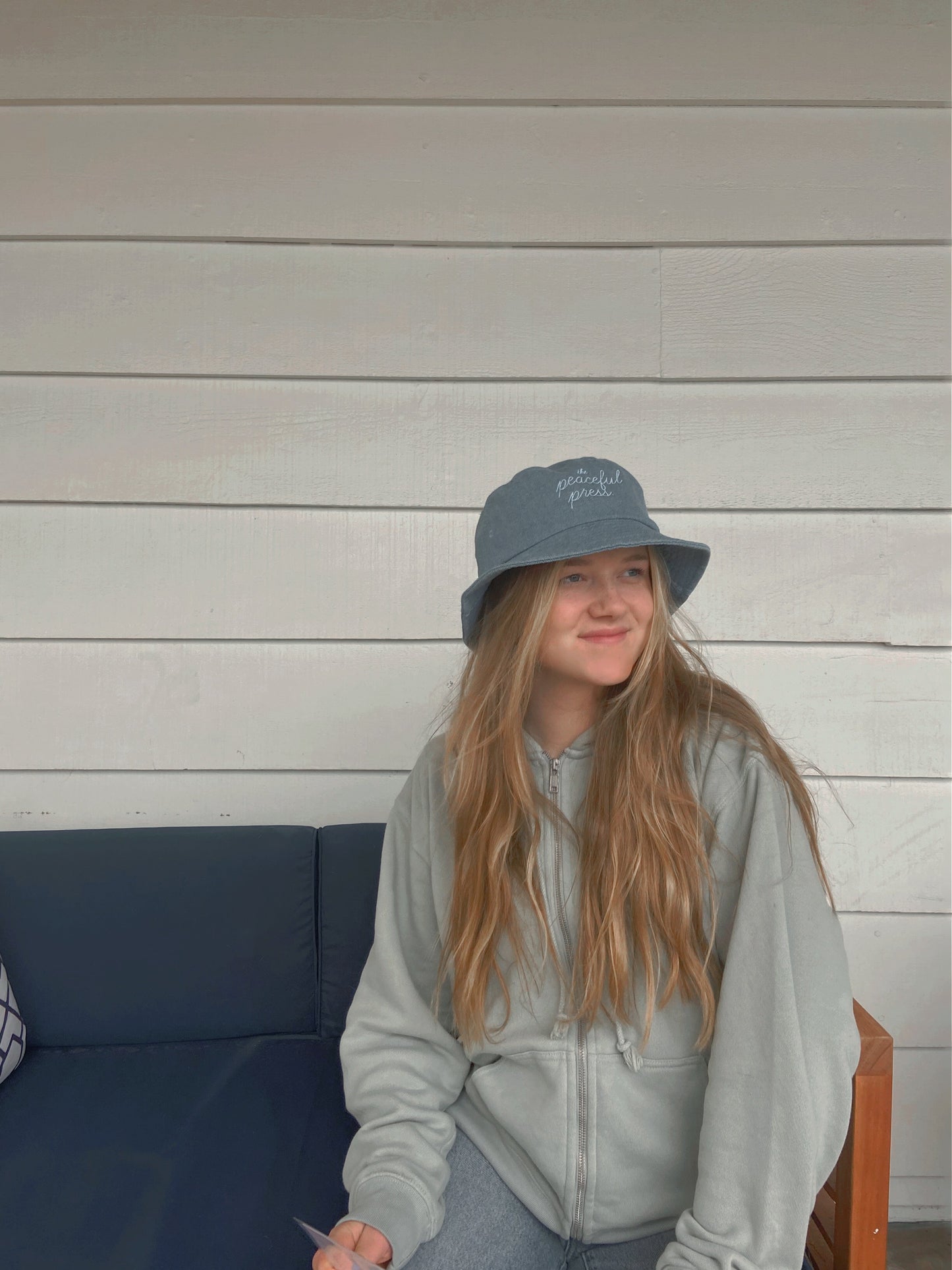 A homeschooler wearing The Peaceful Press on a light denim bucket hat.