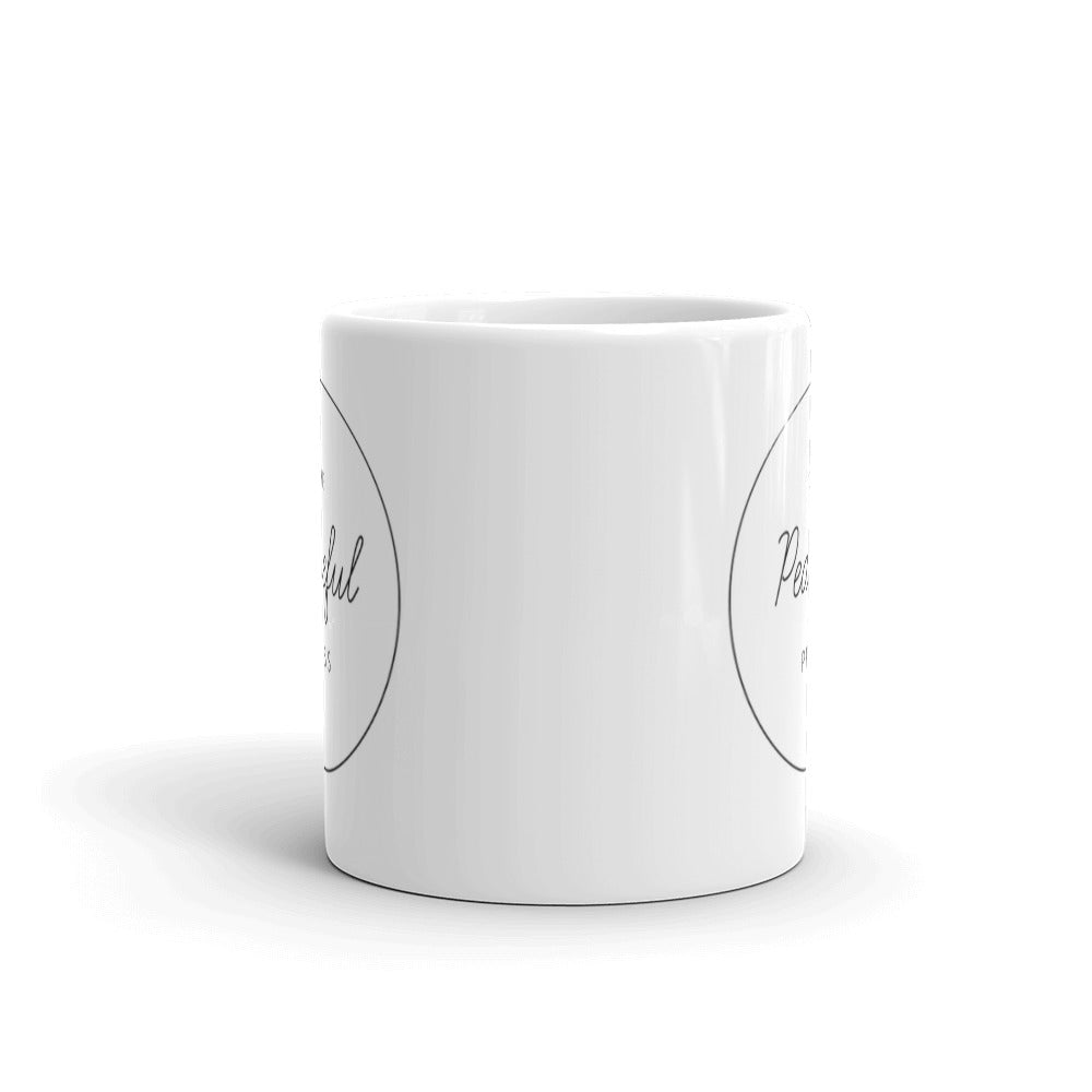 The Peaceful Press Logo on a white ceramic mug on a white background.