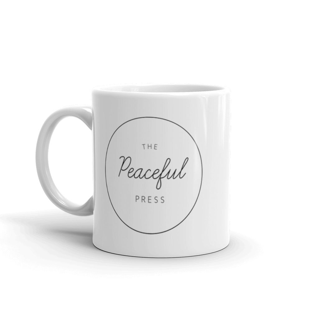 The Peaceful Press Logo on a white ceramic mug on a white background.