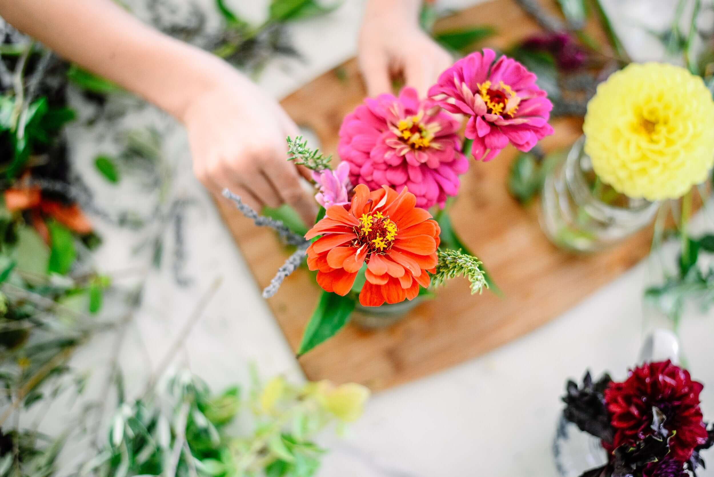 A homeschooler's hands arranging wild flowers in a vase.
