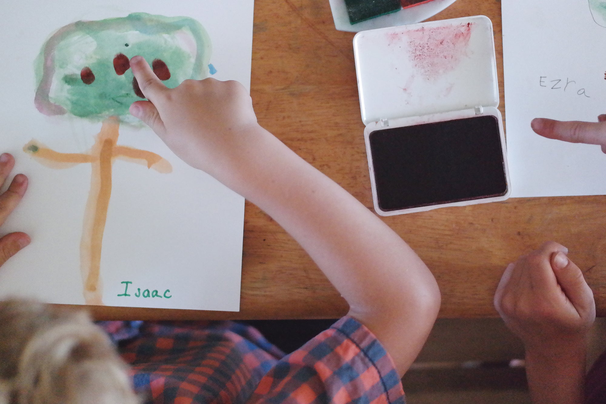 A homeschool kid pointing to his water color painting of an apple tree. 