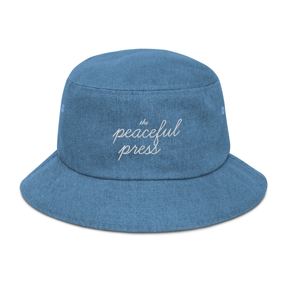 The Peaceful Press on a light denim bucket hat.