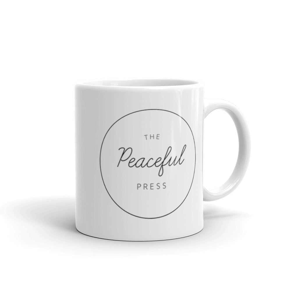 The Peaceful Press Logo on a white ceramic mug on a white background.